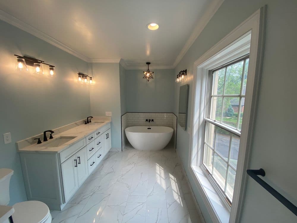 Modern bathroom with freestanding tub, double sink vanity, and large window for natural light.
