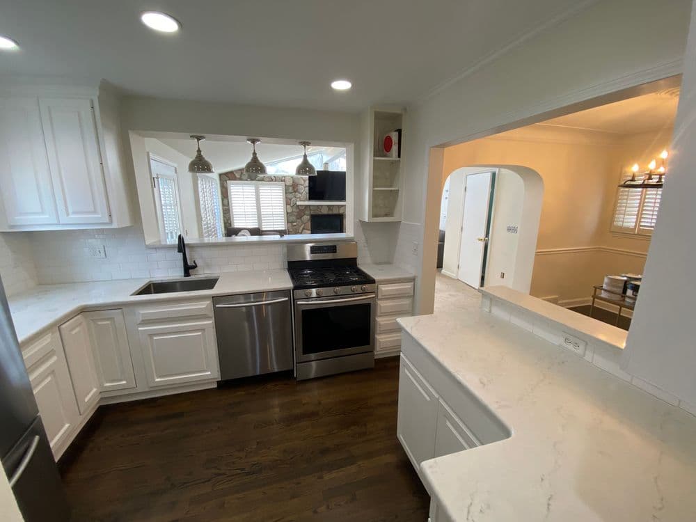 Modern kitchen with stainless steel appliances, white cabinetry, and marble countertops.